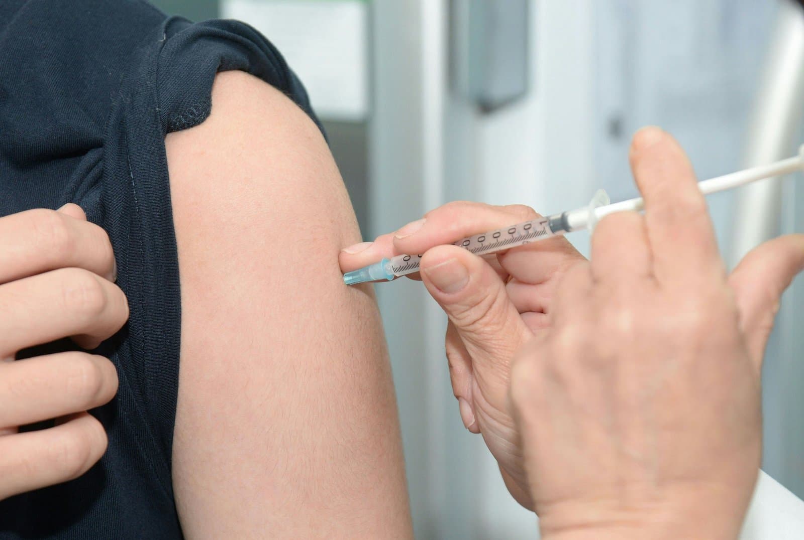 Sundhedsperson giver en vaccination i overarmen på en patient