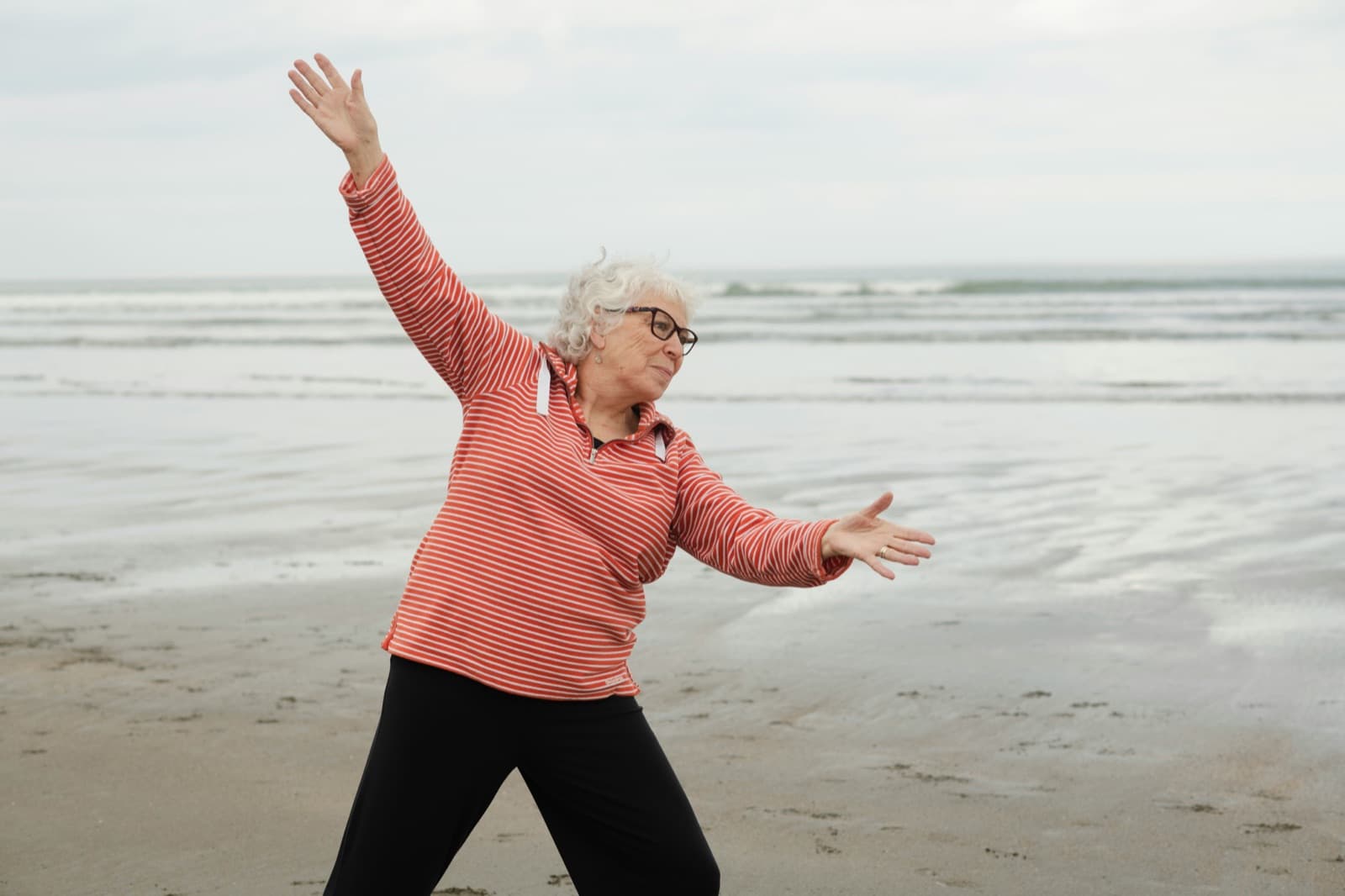 Senior laver afspændingsøvelser ved stranden